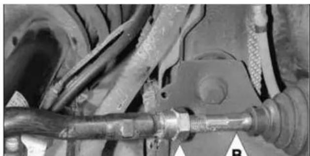 Close-up of automotive suspension system components including hoses and a valve (no visible text or symbols)