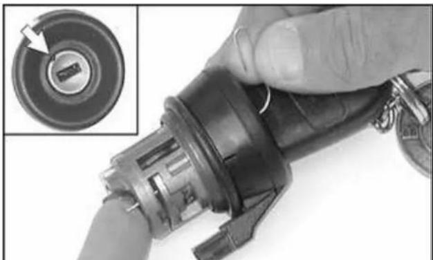 Close-up of a hand holding a black industrial ignition switch with a small inset showing the internal component (no text or symbols visible)