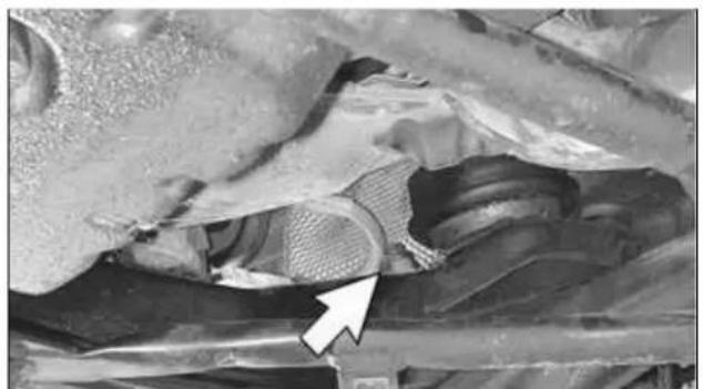Close-up of a mechanical component with a white arrow pointing to a textured surface (no visible text or symbols)