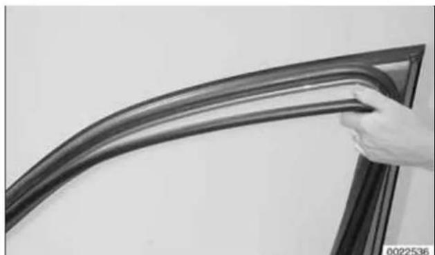 Close-up of a hand holding a curved metal bracket against a plain wall (no text or symbols visible)