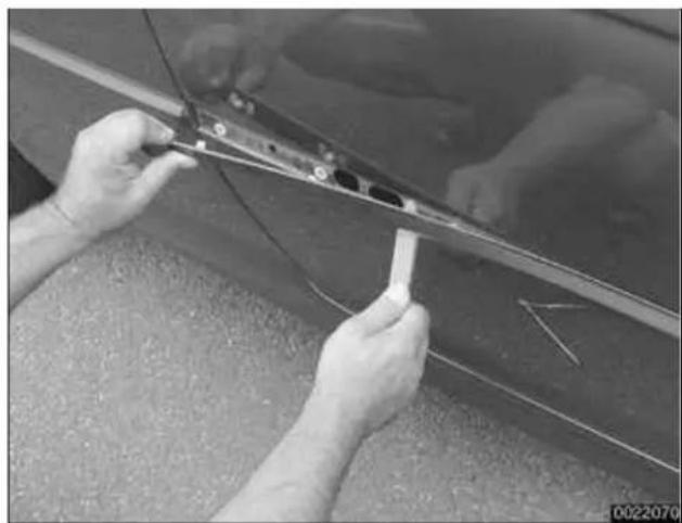 Close-up of hands installing or adjusting a car panel on a surface, no visible text or symbols