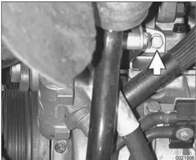 Close-up of mechanical components with a white arrow pointing to a bolted component (no visible text or symbols)