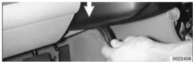 Close-up of a hand using a tool to adjust or install a car seatbelt (no visible text or symbols)