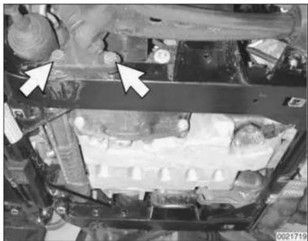 Close-up of a vehicle engine bay with two white arrows pointing to specific components (no visible text or symbols)