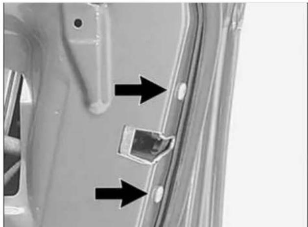 Close-up of a car door panel with two black arrows pointing to a component, no visible text or symbols