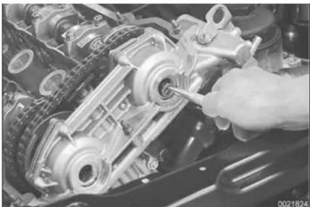 Close-up of a hand using a wrench to adjust internal components of an engine (no visible text or symbols)