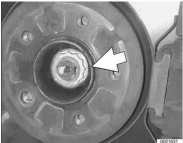 Close-up of a mechanical component with a central hub and bolt holes, marked by an arrow (no text or symbols visible)
