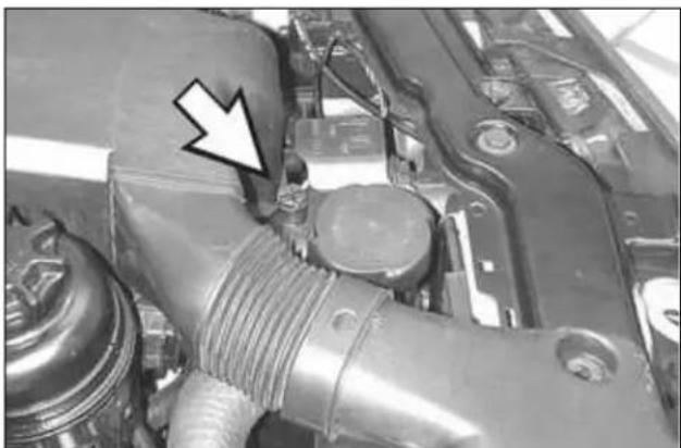 Close-up of an engine component with a white arrow pointing to a specific part (no visible text or symbols)