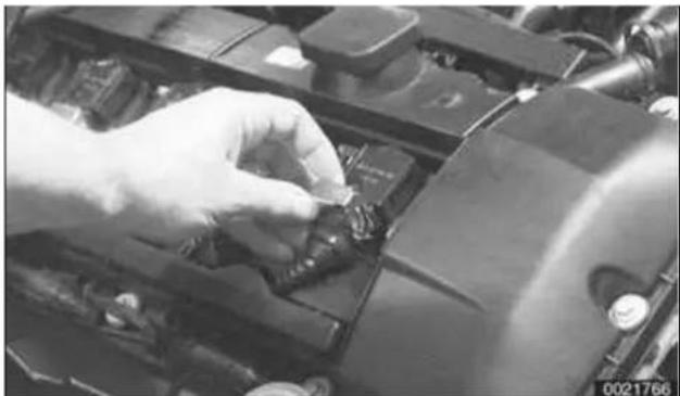 Close-up of a hand using a tool to adjust or install components on a vehicle chassis (no visible text or symbols)