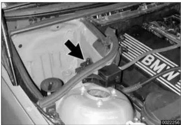 Close-up of a car engine bay with visible components and a black arrow pointing to a component (no text or symbols)