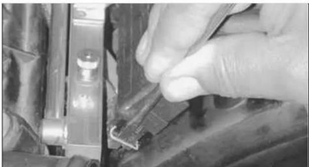 Close-up of a hand adjusting a mechanical component with a tool, no visible text or symbols