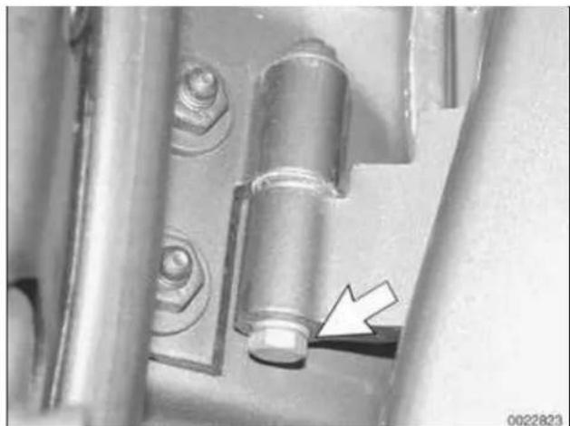 Close-up of a mechanical component with a white arrow pointing to a bolted part (no visible text or symbols)