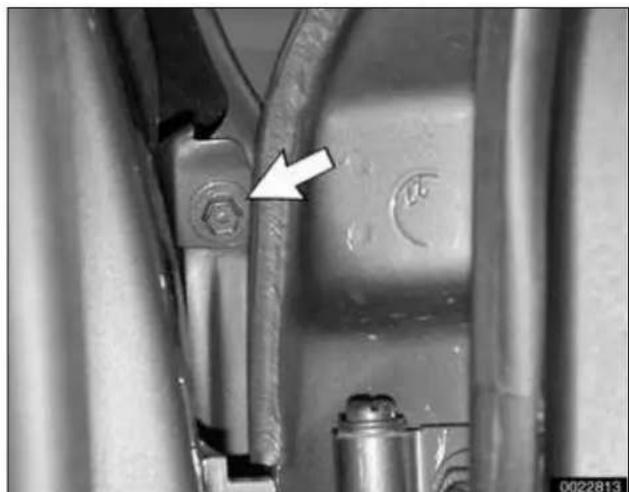 Close-up of mechanical components with a white arrow pointing to a bolted joint (no visible text or symbols)