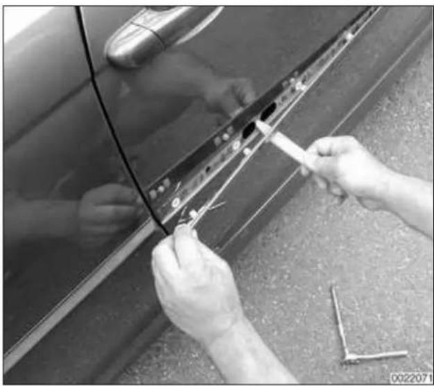 Close-up of hands installing or adjusting a car door panel with a tool (no visible text or symbols)