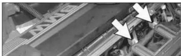 Close-up of a mechanical component with two white arrows pointing to specific parts (no visible text or symbols)