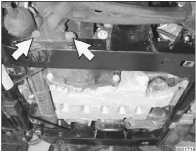 Close-up of an automotive engine bay with two white arrows pointing to a component (no visible text or symbols)