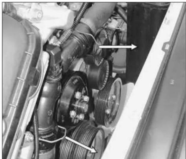 Close-up of automotive engine components including suspension gear, pulleys, and hoses (no visible text or symbols)