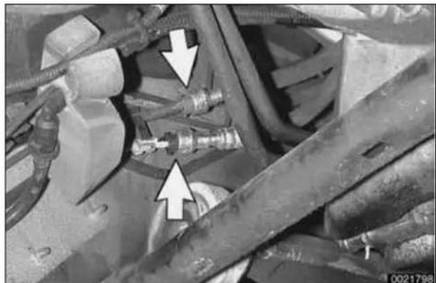 Close-up of mechanical components with white arrows pointing to specific parts (no visible text or symbols)