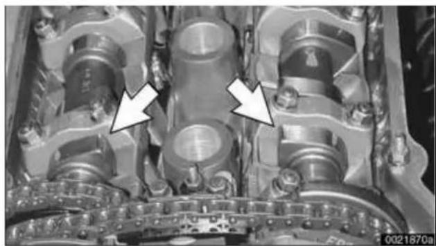 Close-up of an internal combustion engine component with two white arrows pointing to specific parts (no visible text or symbols)