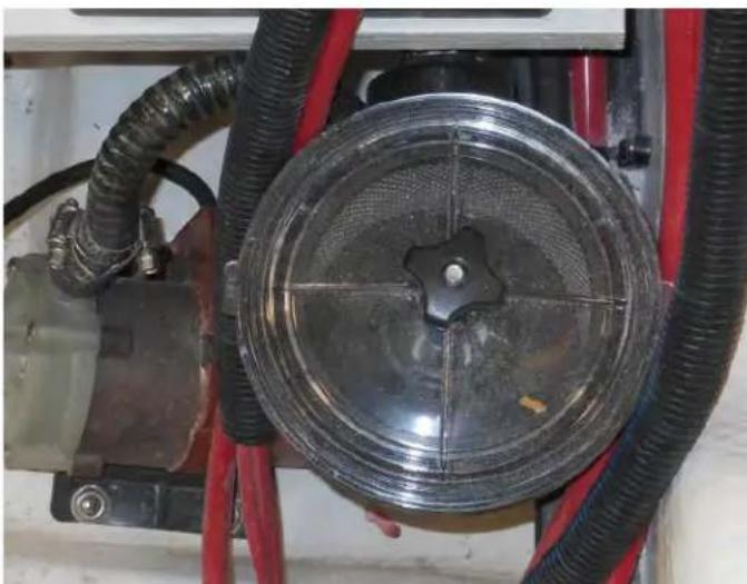 Close-up of a mechanical component with black and red tubing, featuring a circular metallic component and a central hub (no visible text or symbols)