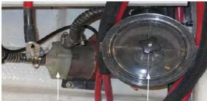 Close-up of a mechanical component with hoses and a central circular dial, no visible text or symbols