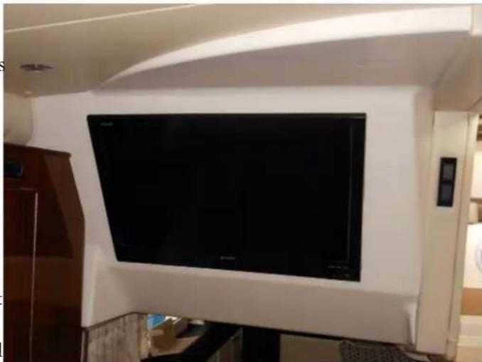 Interior view of a modern living room with a large black TV mounted on a white wall (no visible text or symbols)