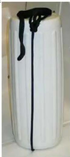 White cylindrical container with black liquid and a string, placed on a surface (no text or symbols visible)