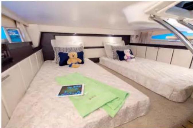 Interior view of a modern luxury hotel with two white furniture beds, each decorated with a teddy bear and green napkin (no visible text or symbols)