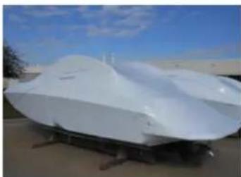 Exterior view of a white, dome-shaped aircraft or spacecraft on a paved surface under a blue sky (no visible text or symbols)