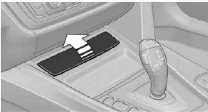 Interior view of a car gear shift lever with a black pad and white arrow indicating direction (no text or symbols)