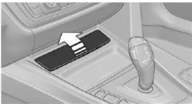 Interior view of a car gear shift lever with a black tab and white arrow indicating direction (no text or symbols)