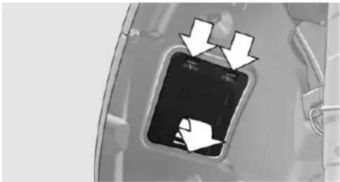 Close-up of a mechanical component with two white arrows pointing to a rectangular opening (no text or symbols visible)