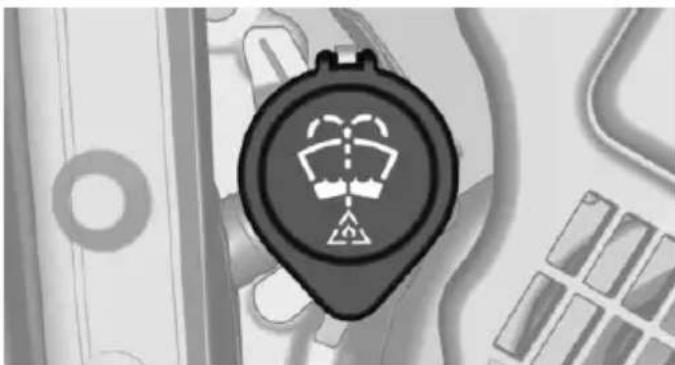 Close-up of a circular mechanical component with a warning symbol, placed on a grid-patterned surface (no text or symbols visible)