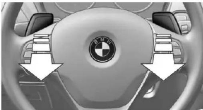 Interior view of a car dashboard with BMW logo and directional arrows indicating steering wheel (no text or symbols)