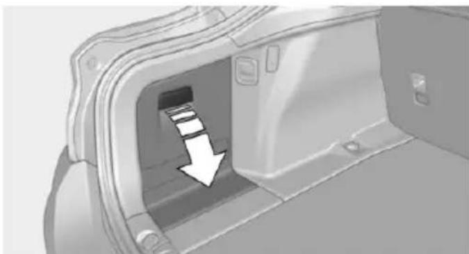Interior view of a vehicle showing a car trunk with an arrow pointing to the side panel (no text or symbols present)