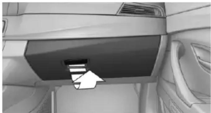 Interior view of a car showing the dashboard and side panel with an arrow pointing to a component (no text or symbols visible)