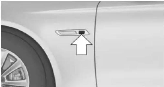 Close-up of a car's side panel with an arrow pointing to a small component (no text or symbols visible)