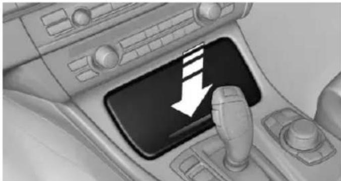 Interior view of a car gear shift control panel with a white downward arrow indicating left motion (no text or symbols present)