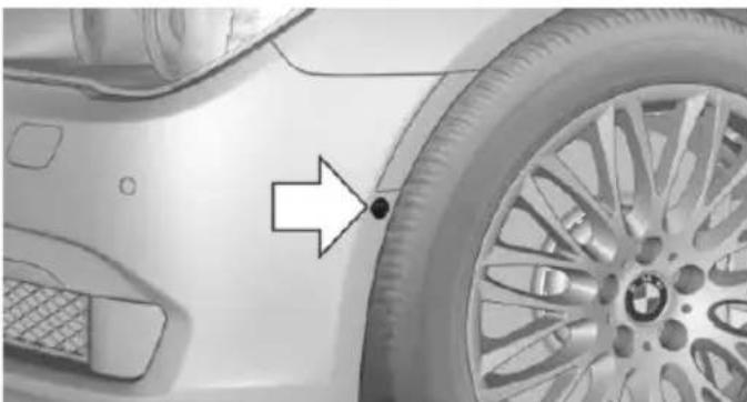 Close-up of a car wheel rim with a BMW logo and an arrow pointing to a specific part (no text or symbols visible)