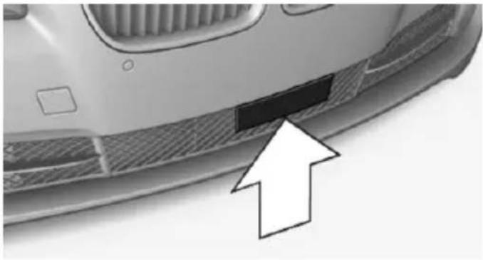Close-up of a car's front bumper with a black rectangular patch and an arrow pointing to it (no text or symbols visible)