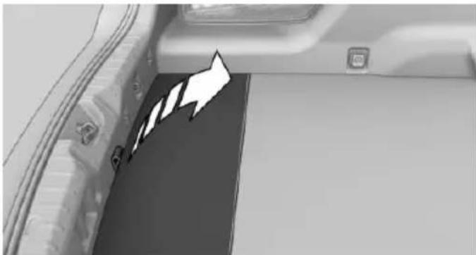Interior view of a vehicle showing a car trunk and side panel with a white arrow pointing to a section (no text or symbols visible)