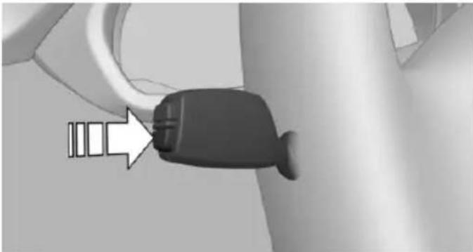Close-up of a black car seatbelt connector with a white arrow pointing to it, against a plain background (no text or symbols)