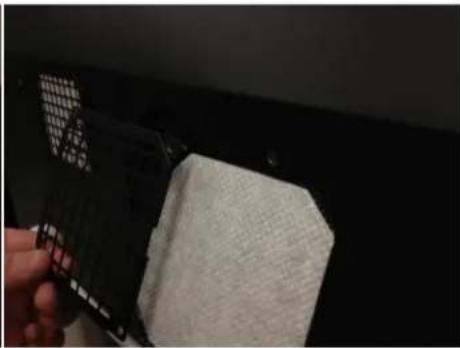 Close-up of a hand holding a black rectangular object with a white textured surface, against a dark background (no visible text or symbols)