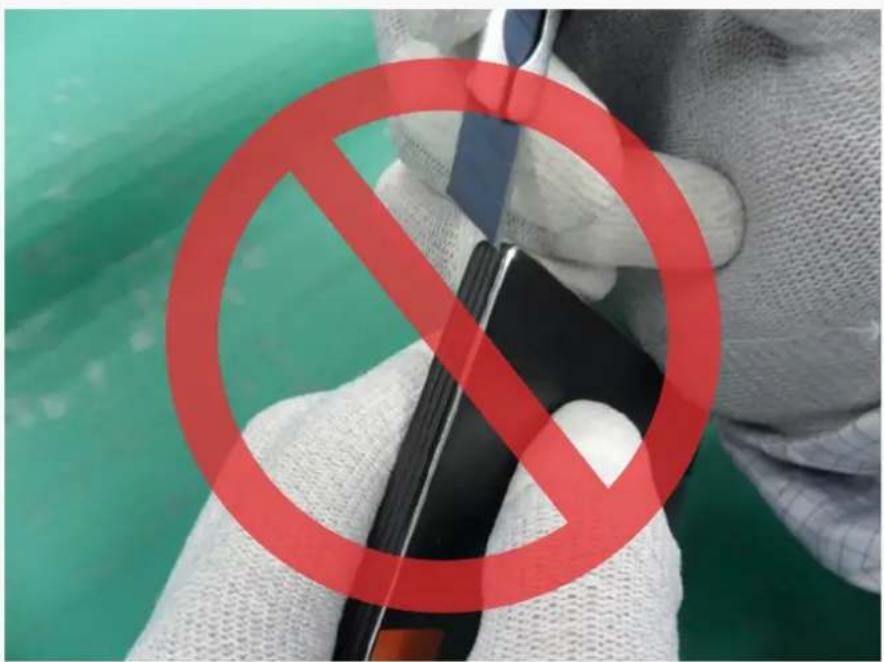 Close-up of hands holding a red prohibition symbol over a device, with green background and partial text visible.