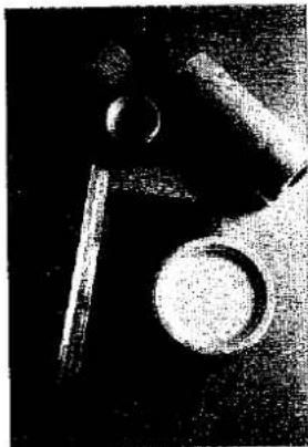 Nahaufnahme eines mechanischen Bauteils mit kreisförmiger Basis und zwei hervorstehenden Stangen (kein sichtbarer Text oder Symbole)
