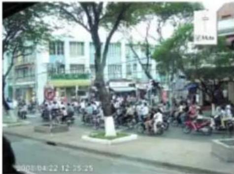 Street photo showing a crowded urban intersection with visible store signboards and date stamp at bottom