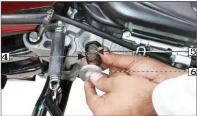 Close-up of a car suspension system with numbered components and a hand adjusting the valve assembly