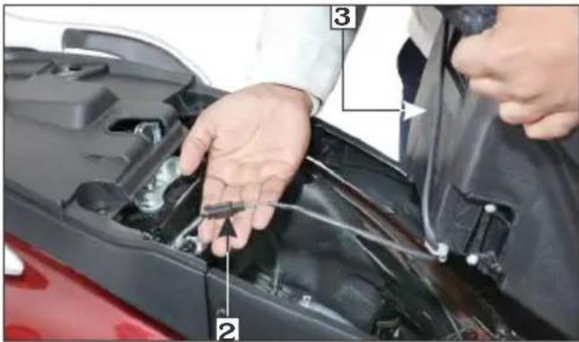 Close-up of hands installing or adjusting a car engine compartment with numbered parts labeled 2 and 3