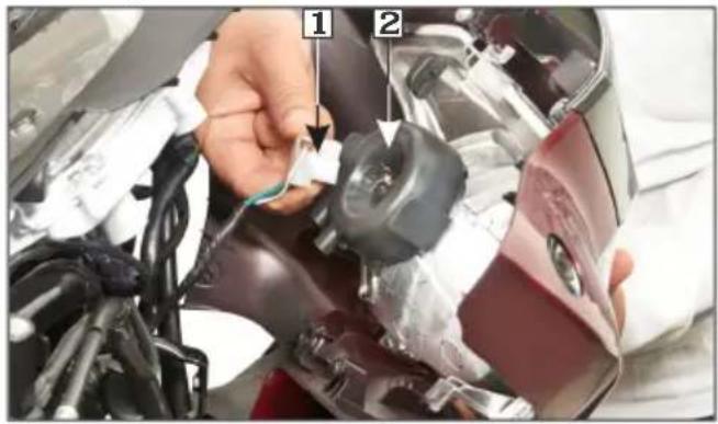 Close-up of a car's helmet assembly with labeled parts, showing hands installing cable and plastic components