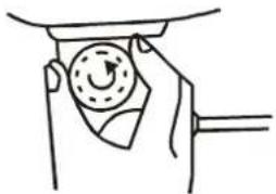 Hand holding a circular gauge or dial with a pointer, no text or symbols visible
